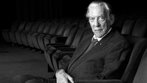 Der kanadische Schauspieler Donald Sutherland sitzt seitlich zur Kamera auf einem Kinosessel und blickt in die Kamera (Archivbild von 2017) © picture alliance/AP Images | Chris Pizzello Foto: Chris Pizzello