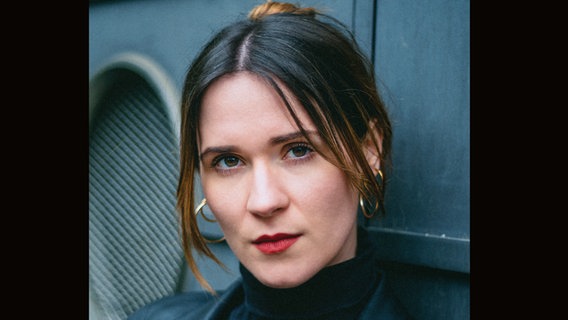 Eine junge Frau mit geschminkten Lippen und hochgesteckten Haaren lehnt an einer Wand - Regisseurin Tamara Deni ©  Charlot van Heeswijk/Agentur Fischer & Partner FILM TV THEATER/dpa Foto:  Charlot van Heeswijk