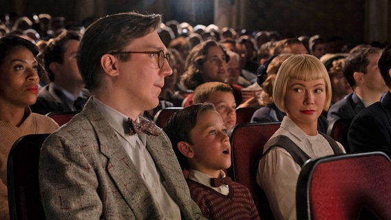 Burt Fabelman (Paul Dano), young Sammy Fabelman (Mateo Zoryan Francis-DeFord) and Mitzi Fabelman (Michelle Williams) are sitting in the packed cinema - in Steven Spielberg's movie 