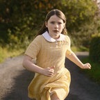 Ein Mädchen in gelbem Kleid und wehenden Haaren läuft einen Weg hinunter © Neue Visionen Filmverleih 