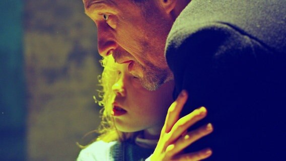 Ein Mann hält ein Kind im Arm - in einer Filmszene aus "Tian - Das Geheimnis der Schmuckstraße"  "Nordlichter"-Mysteryfilms von Damian Schipporeit © Fiction 2.0 für NDR 
