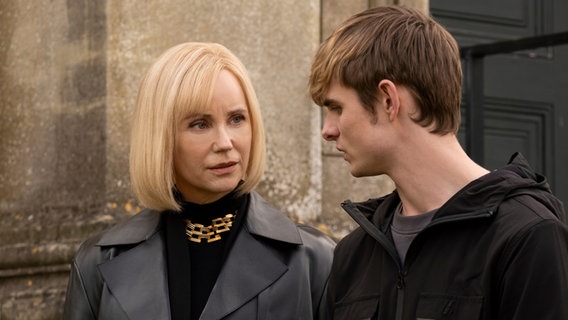 "Alex Rider - Zielscheibe": Mrs. Rothman (Sofia Helin) und Alex (Otto Farrant) stehen nebeneinander im Freien vor einer steinernen Wand. Sie blicken sich mit ernster Miene an. © ZDF/Joss Barratt, nur für diese Sendung 