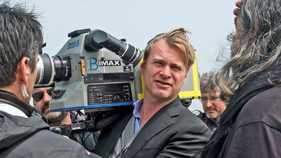 Am Set vom Film "Dunkirk": Regisseur Christopher Nolan, umringt von seiner Crew, hält eine Imax-Filmkamera auf der Schulter © 2017 WARNER BROS. ENTERTAINMENT INC 