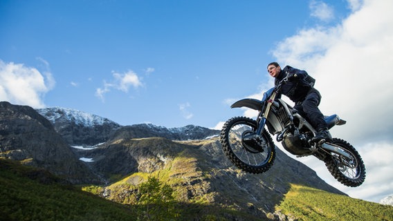 Ein Mann springt auf einem Motorrad durch die Luft -  Szene mit Tom Cruise aus "Mission Impossible 7 - Dead Reckoning Teil Eins" © 2023 Paramount Pictures. 