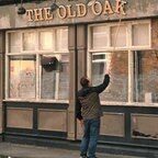 Ein Mann repariert den Schriftzug "The Old Oak" über einem Pub © picture alliance/dpa/Wild Bunch Germany | - 