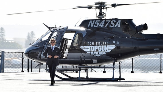 Actor Tom Cruise gets out of a helicopter with the inscription on it 
