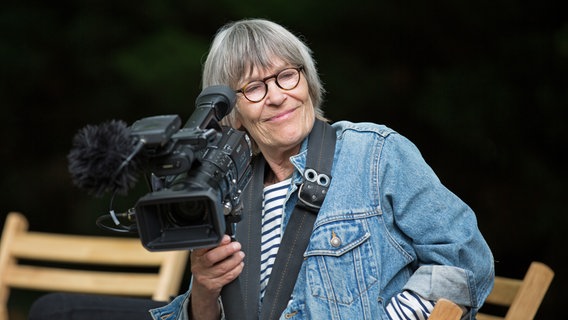 Porträt einer lächelnden Gisela Tuchtenhagen mit Filmkamera in der Hand aus dem Jahr 2014. © Andy Michaelis 