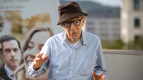 Woody Allen steht mit einem Hut auf dem Kopf vor einem Filmplakat. © picture alliance/dpa/EUROPA PRESS | Lorena Sopêna 