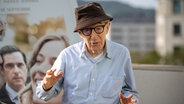 Woody Allen steht mit einem Hut auf dem Kopf vor einem Filmplakat. © picture alliance/dpa/EUROPA PRESS | Lorena Sopêna 