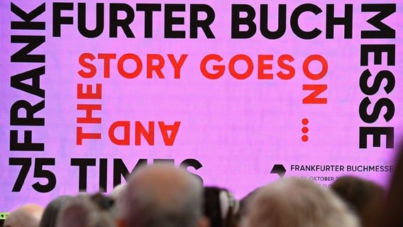 Auf einem LED-Monitor wird das Motto "Frankfurter Buchmesse. 75 times. And the story goes on..." präsentiert. © picture alliance/dpa | Arne Dedert 