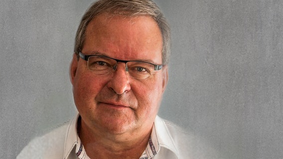 Ein Herr mittleren Alters mit grauem Haar und Brille blickt freundlich in die Kamera. Der Hintergrund ist grau. © privat 