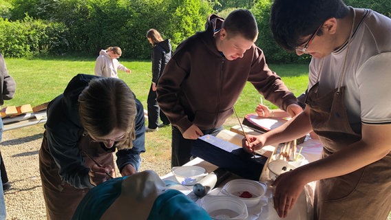 Jugendliche gestalten im Museumspark Kalkriese Varusmasken als Friedenszeichen, in der Mitte Leon Glüsenkamp. Jugendliche gestalten im Museumspark Kalkriese Varusmasken als Friedenszeichen, in der Mitte Leon Glüsenkamp. © Karoline Kempe