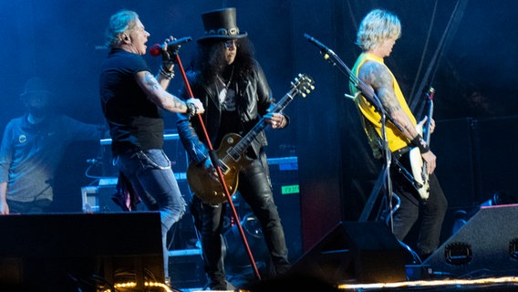 Axl Rose und Slash von Guns N' Roses spielen auf einer Bühne, im Hintergrund der zweite Gitarrist. © picture alliance / TT NYHETSBYR?N | TT 