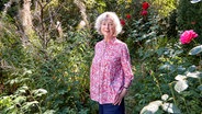 Ulla Hahn steht in einem verwilderten Garten und lächelt. © picture alliance/dpa | Georg Wendt 
