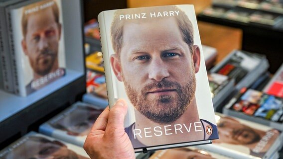 Jemand hält Prinz Harrys Autobiografie "Spare" in der Hand. © picture alliance/dpa Foto: Jens Kalaene