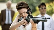Eine Frau zielt mit einem Gewehr. © WDR/Constantin Film/Michel Vertongen 