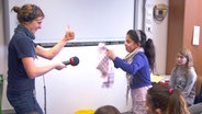 Jantje Fischhold vom NDR Projekt "Hörspiel in der Schule" macht mit einer Schülerin der Elbschule und einem Geschirrtuch Fledermausgeräusche. © NDR 