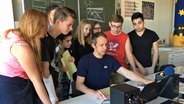 Schüler der Klasse 8b der Schulrat-Habermalz-Schule schauen Producer Marko Pauli beim Arbeiten am Computer über die Schulter. © NDR Foto: Janine Lüttmann