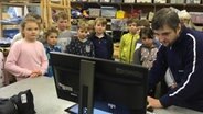 Kinder schauen gemeinsam mit einem NDR Producer auf einen Computerbildschirm. © NDR Foto: Janine Lüttmann