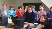 Marko Pauli arbeitet mit Kindern der Grundschule Salzhausen/Eyendorf am Computer. © NDR Foto: Janine Lüttmann