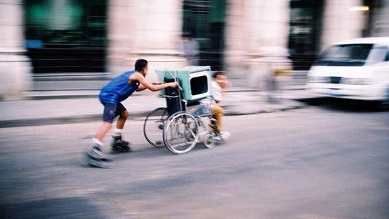 Ein Jugendlicher schiebt einen weiteren Jugenlichen im Rollstuhl. © vespa200 / photocase.de Foto: vespa200