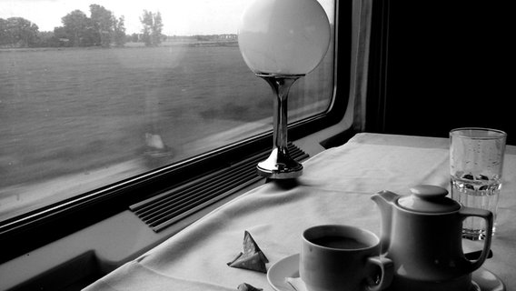 Blick aus dem Fenster eines fahrenden Zugs. Im Vordergrund steht ein Teeservice auf einem Tisch. © frau.L. / photocase.de Foto: frau.L.