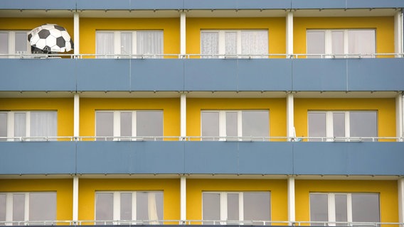 Weimar Nord: Ein Sonnenschirm in Form eines Fußball steht auf einem Balkon eines zehngeschössigen Hochaus. © IMAGO/Thomas Müller 