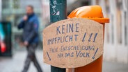 Schild mit der Aufschrauf Impfpflicht lehnt an einem Mülleimer © picture alliance/dpa/APA | Fotokerschi.At / Kerschbaummayr 