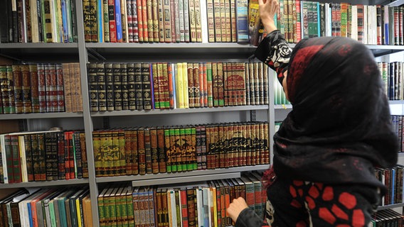 Eine Studentin nimm ein Buch aus einem Regal © picture alliance / dpa Foto: Franziska Kraufmann