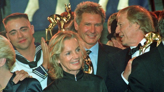 Jil Sander neben Wolfgang Petersen und vor Harrison Ford bei der Bambi-Verleihung 1997. © picture alliance / ASSOCIATED PRESS | FRITZ REISS 