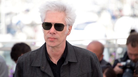 Jim Jarmusch im Porträt, hinter ihm stehen Pressefotografen. © picture alliance / Cannes | Alberto Terenghi/Cannes / IPA 