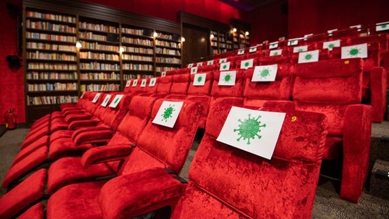 Sitzplätze in einem Kino sind sind mit Zetteln mit aufgedrucktem angedeuteten Corona-Virus-Symbol abgesperrt. © picture alliance/dpa Foto: Julian Stratenschulte
