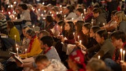Menschen mit Kerzen sitzen auf dem Opernplatz in Hannover © IMAGO/epd/Paul-Philipp Braun Foto: Paul-Philipp Braun