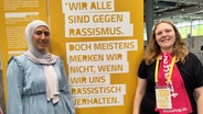 Zwei Frauen stehen vor einem Plakat © NDR 