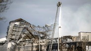 Ein Feuerwehrmann auf einer Drehleiter löscht den Brand der Historischen Börse in Kopenhagen - es ist nur noch das Gerippe zu erkennen © Mads Claus Rasmussen/Ritzau Scanpix Foto/AP +++ dpa-Bildfunk +++ Foto: Mads Claus Rasmussen