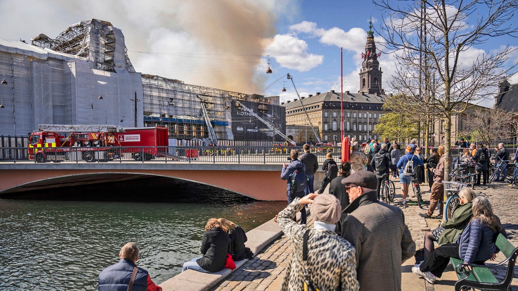 Menschen vor der durch Brand stark beschädigten Historischen Börse in Kopenhagen - es ist nur noch das Gerippe zu erkennen