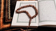 Eine hölzerne Gebetskette liegt auf einem Koran. © Fotolia Foto: BEGY Production