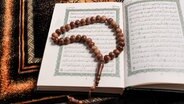 Eine hölzerne Gebetskette liegt auf einem Koran. © Fotolia Foto: BEGY Production