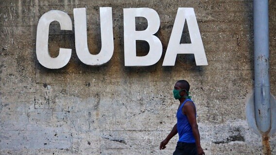 Ein Mann mit Mundschutz geht an einer Wand mit der Aufschrift "Cuba" vorbei © Guillermo Nova/dpa +++ dpa-Bildfunk Foto: Guillermo Nova
