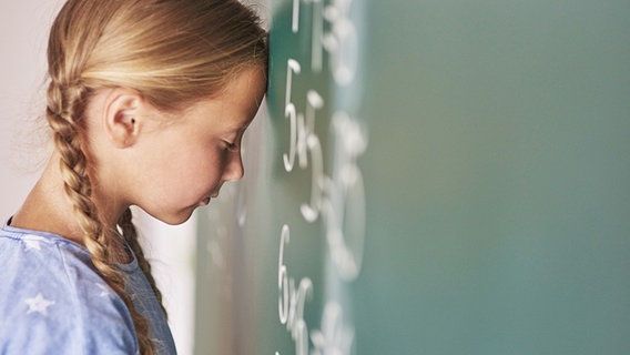 Ein Mädchen lehnt ihren Kopf an eine Tafel. Ihre Augen sind geschlossen. © fotolia.com Foto: gpointstudio