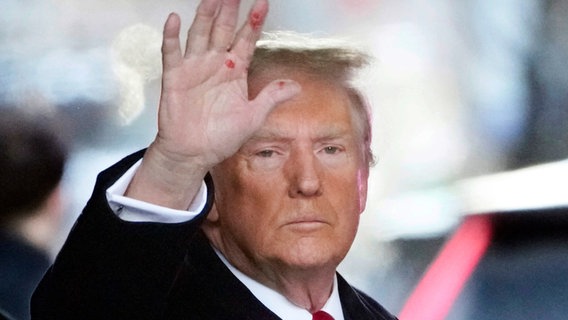 Donald Trump, Präsidentschaftskandidat und ehemaliger Präsident der USA hält eine verschmierte Hand hoch. © dpa-Bildfunk/AP/dpa Foto: Seth Wenig