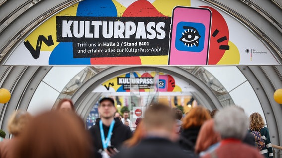 Besucher gehen unter einer Werbung für den Kulturpass über die Leipziger Buchmesse. © picture alliance/dpa | Jan Woitas 