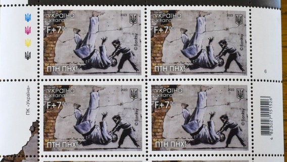 Das Bild zeigt eine Briefmarke, auf der ein kleiner Junge, einen erwachsenen Mann, der dem russischen Präsidenten Wladimir Putin - selbst begeisterter Judokämpfer - ähnelt, in einem Judokampf zu Boden wirft. © picture alliance/dpa/kyodo Foto: kyodo