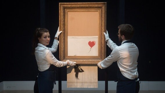Eine Frau und ein Mann halten Banksys Bild "Love is in the Bin" © picture alliance / Photoshot | - 