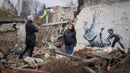 Zwei Frauen fotografieren sich vor einem Streetart Bild von Banksy © picture alliance / ASSOCIATED PRESS | Andrew Kravchenko Foto: Andrew Kravchenko