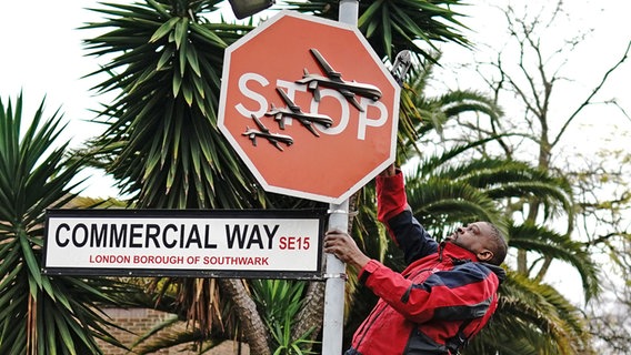 Ein Mann schraubt ein Stopschild, auf dem drei Drohnen abgebildet sind ab © picture alliance Foto: Aaron Chown