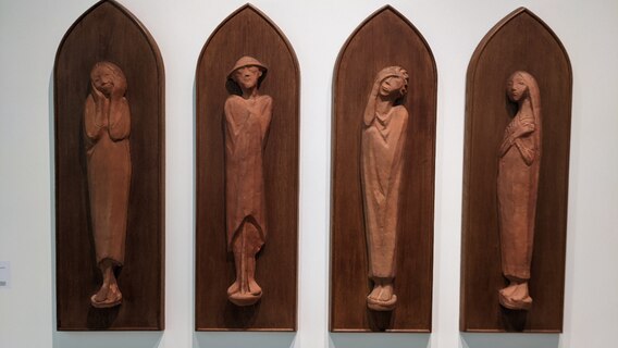 Vier hochformatige Terrakotten des Künstlers Ernst Barlach, rechts und links daneben stehen zwei Frauen, die die Kunstwerke lächelnd anschauen. Vier hochformatige Terrakotten des Künstlers Ernst Barlach, rechts und links daneben stehen zwei Frauen, die die Kunstwerke lächelnd anschauen. © Katja Bülow /NDR Foto: Katja Bülow