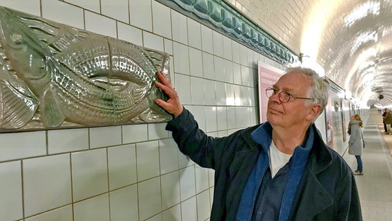 Der Keramikmeister Hans Kuretzky berührt eines der von ihm restaurierten Kachelreliefs im alten Elbtunnel © NDR Foto: Stefanie Wittgenstein