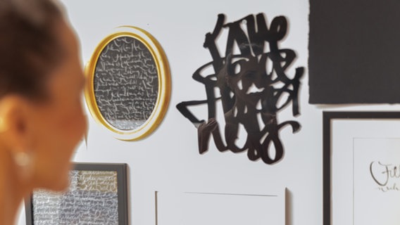 Jeannine Platz betracht ihre kalligrafischen Arbeiten an der Wand ihres Ateliers © NDR.de Foto: Christina Grob