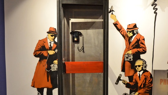 In dieser abgehörten Telefonzelle können sich Besucherinnen und Besucher abbilden lassen - Bild einer Replik von Kunst des Graffiti-Künstlers Banksy in der Hamburger Ausstellung "The Mystery of Banksy - A Genius Mind" © NDR Foto: Patricia Batlle